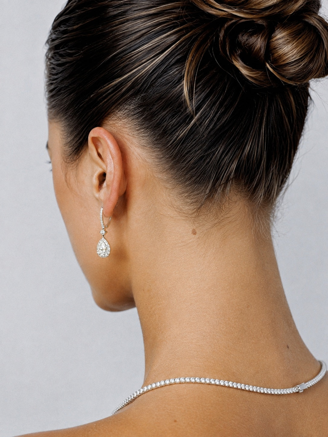 Pear-shaped diamond drop earrings worn by a model