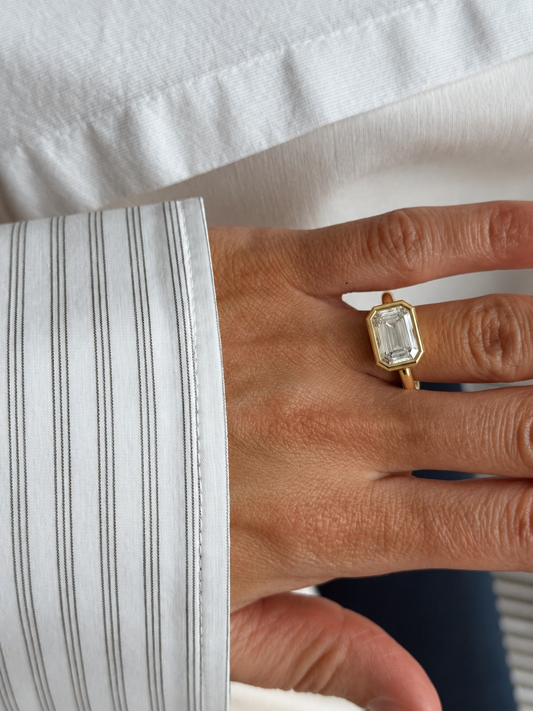 Emerald-cut ring beside a striped shirt cuff