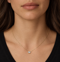 East-west emerald-cut diamond necklace in yellow gold worn with a black top