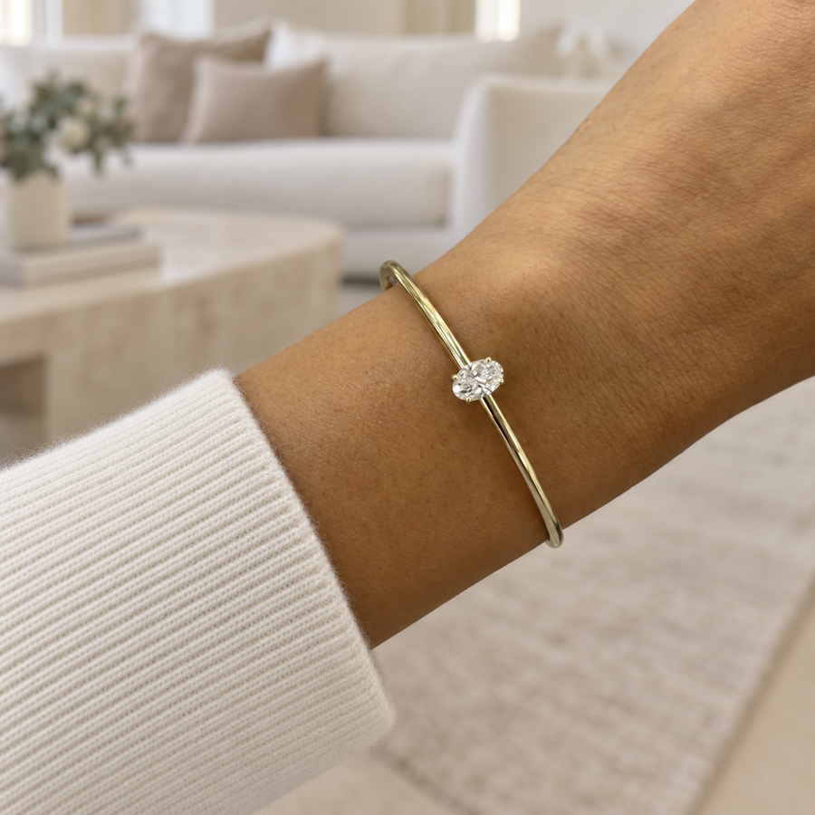 Oval diamond bangle in yellow gold worn on a wrist