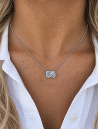 Pear and emerald-cut diamond necklace in white gold worn with a white shirt
