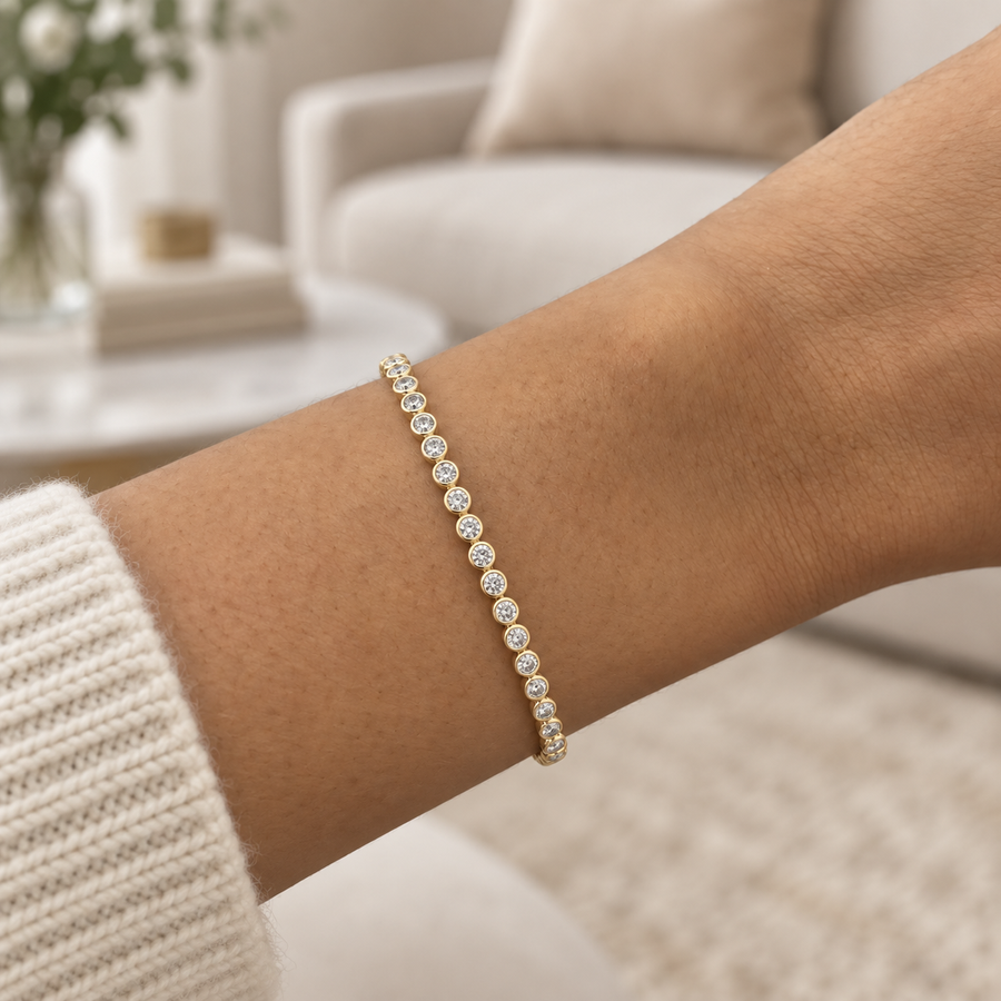 Round bezel diamond tennis bracelet in yellow gold worn on a wrist