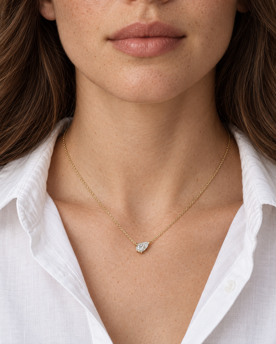 Tilted pear diamond necklace in yellow gold worn with a white shirt