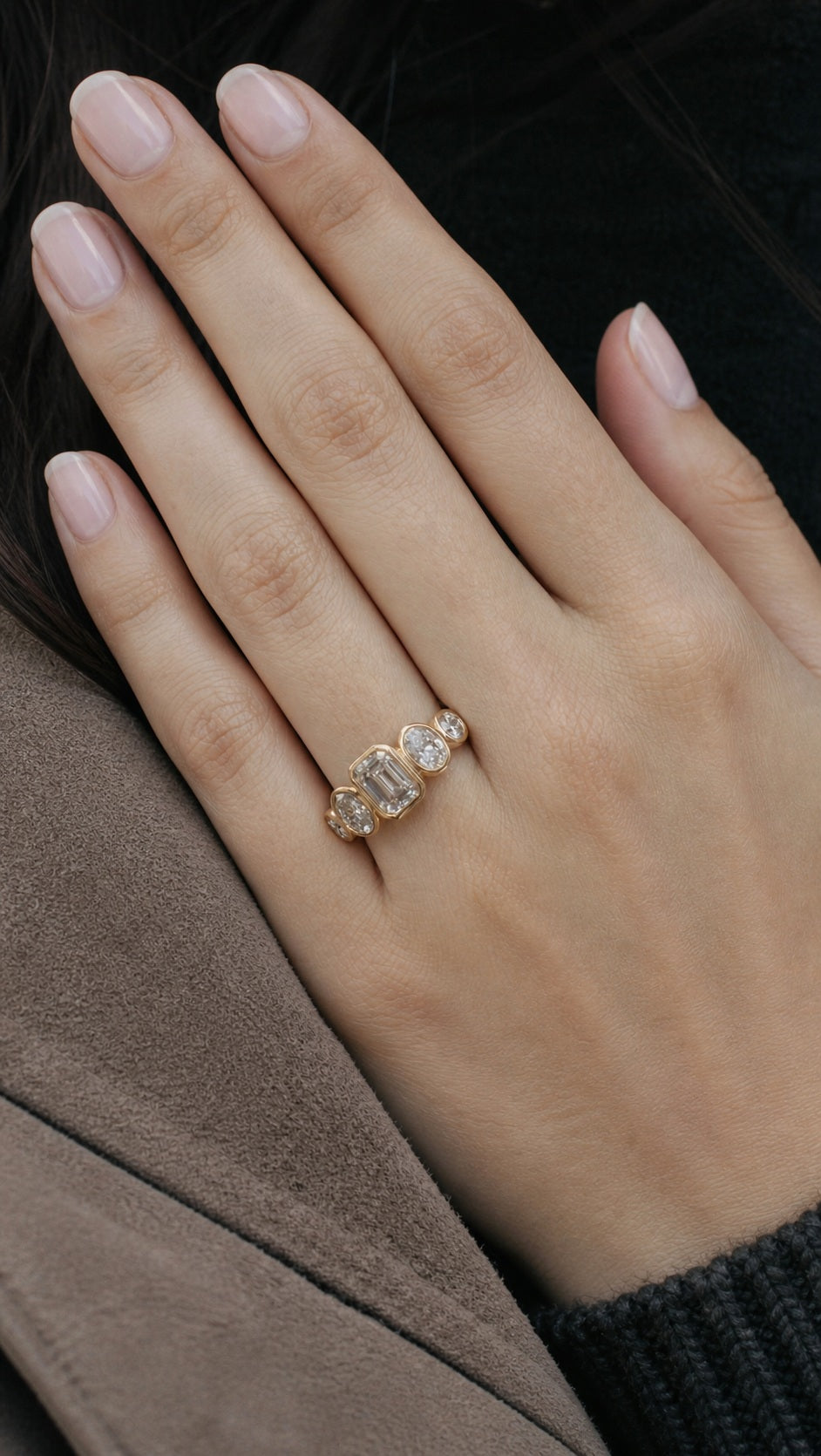 Five-stone bezel engagement ring on the ring finger with milky pink nails