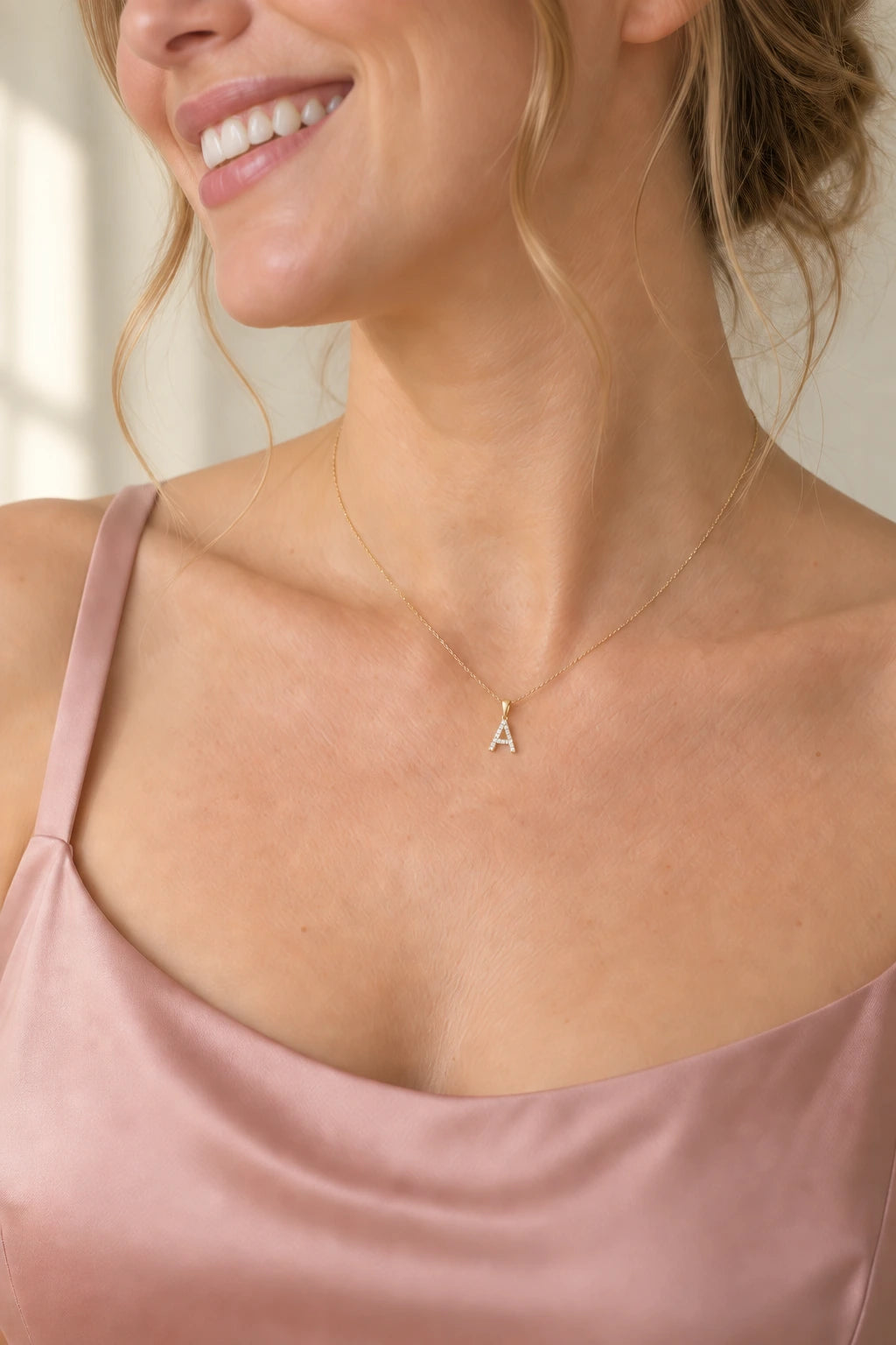 Delicate pavé A initial necklace on a fine gold chain, worn with a blush satin dress