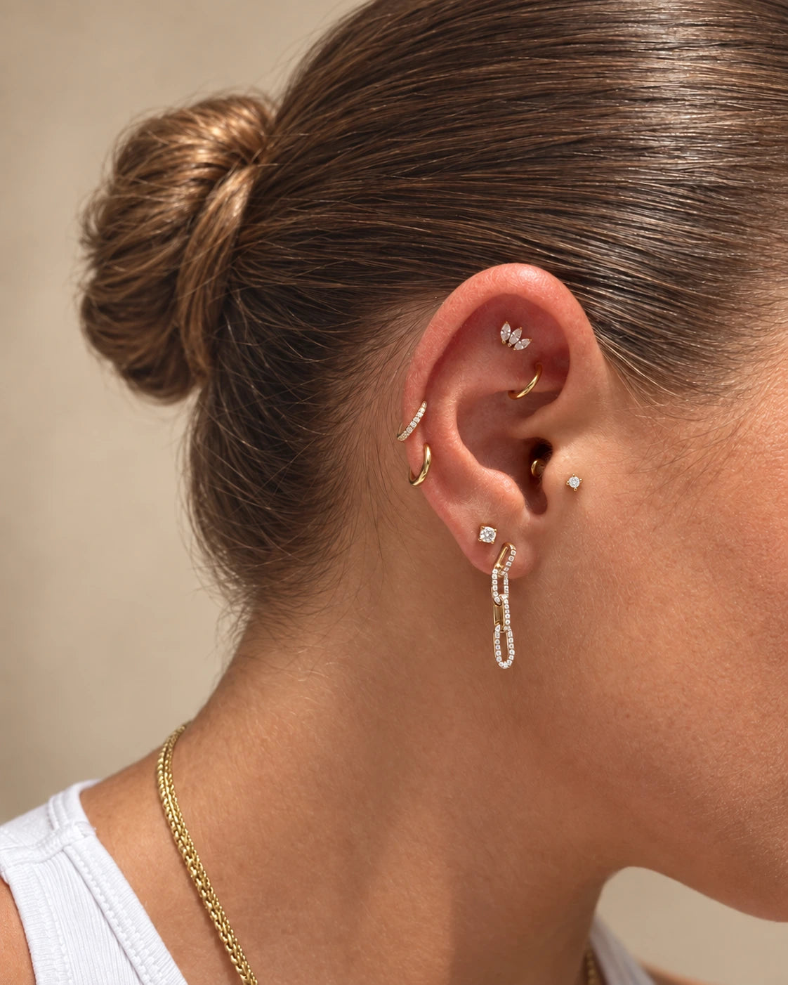 A curated ear stack of yellow gold hoops, delicate diamond studs and a diamond link drop earring