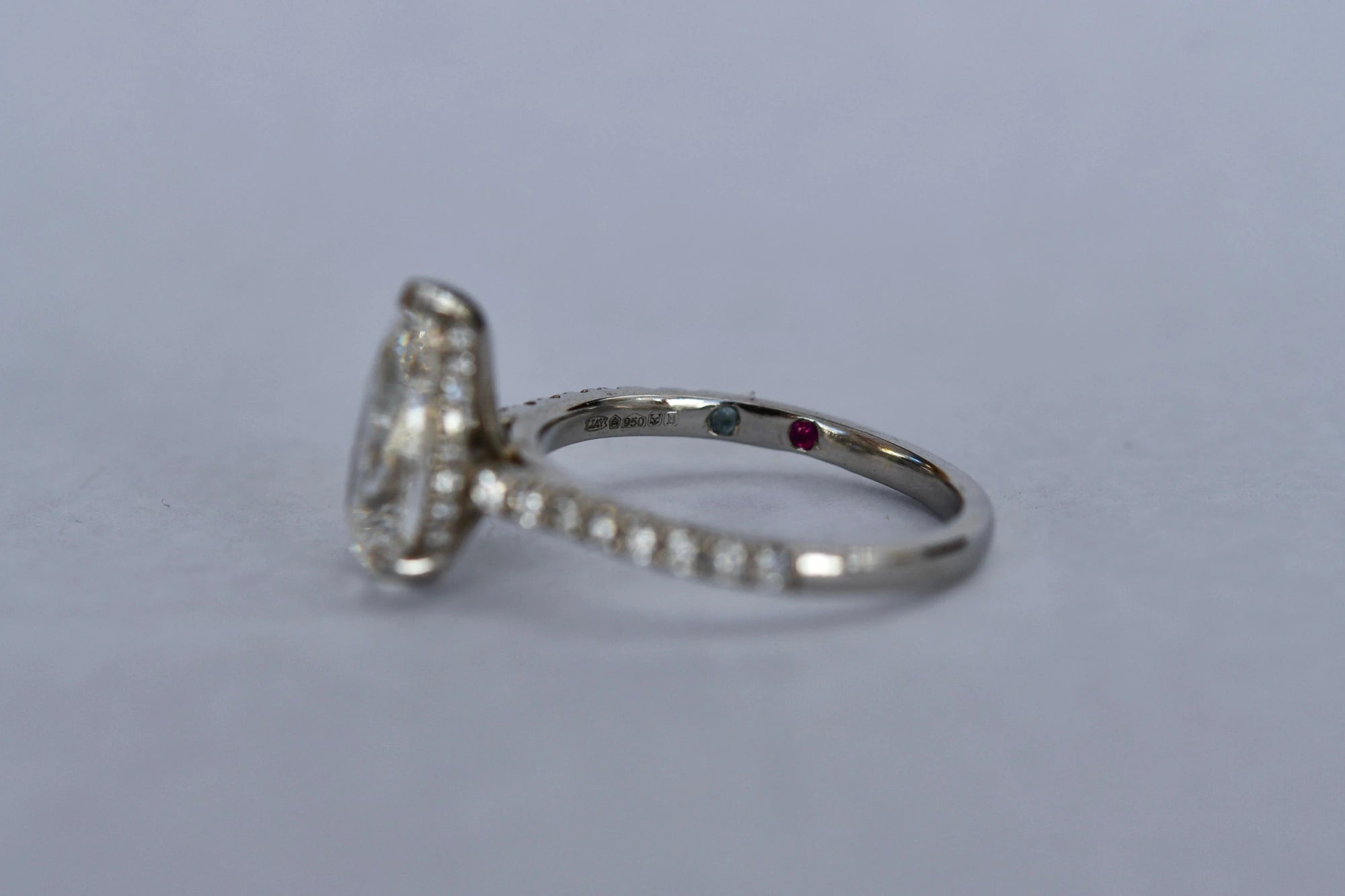 LIAV platinum diamond ring showing five hallmarks inside the band beside two coloured stones