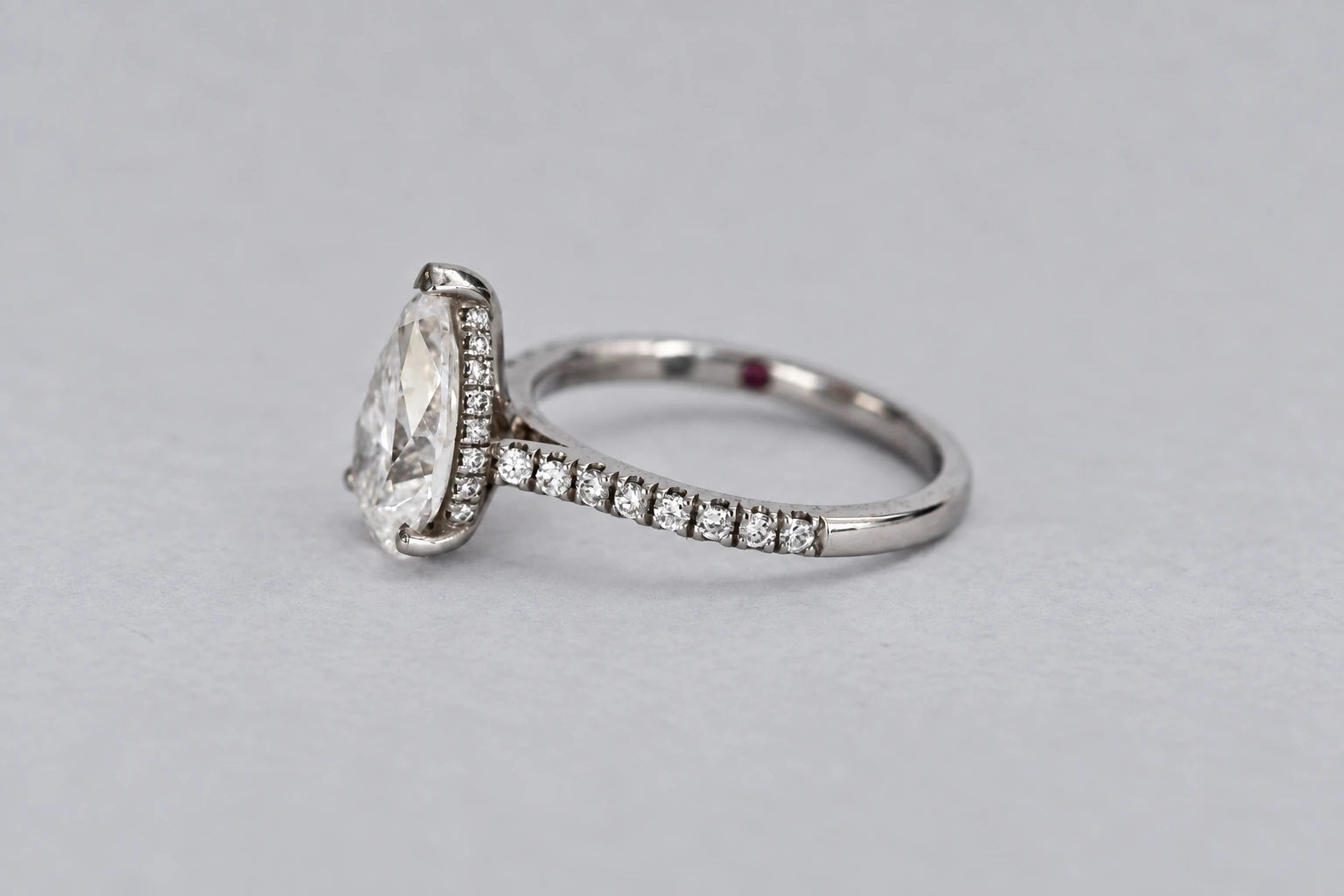 Side view showing the hidden halo and pavé detailing beneath the pear diamond